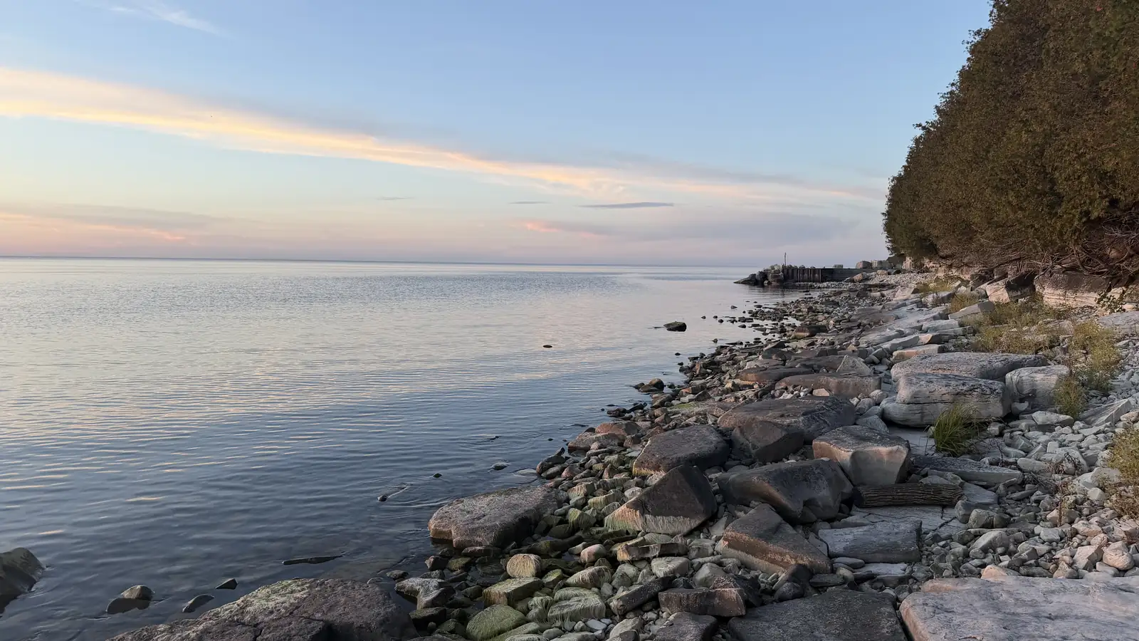 Calm Lake Michigan water and a rocky limestone shoreline at sunset in Ellison Bay, Wisconsin