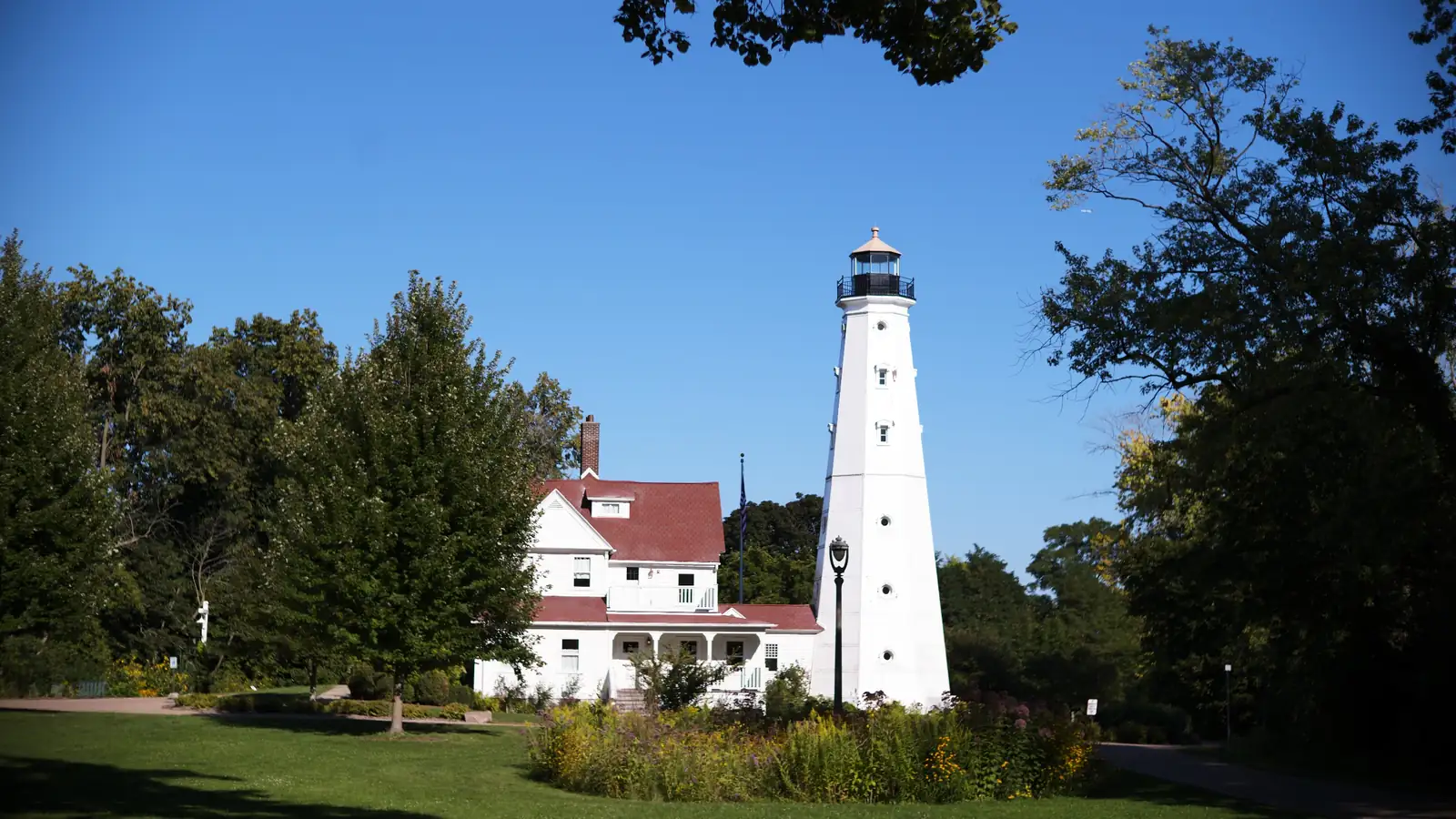 The white North Point Lighthouse and keeper's house under a clear blue sky in Lake Park, Milwaukee